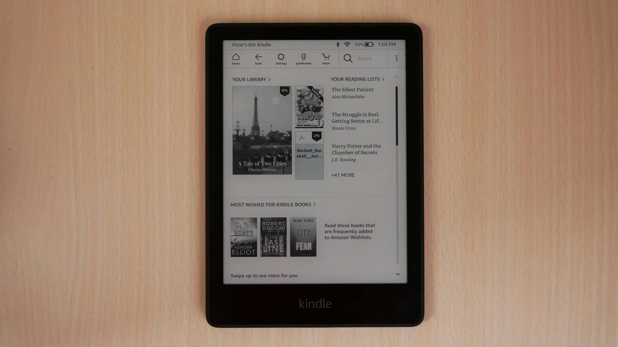 Amazon Kindle Paperwhite 11th Generation 2021 on a brown wooden table with its display turned on and facing upwards